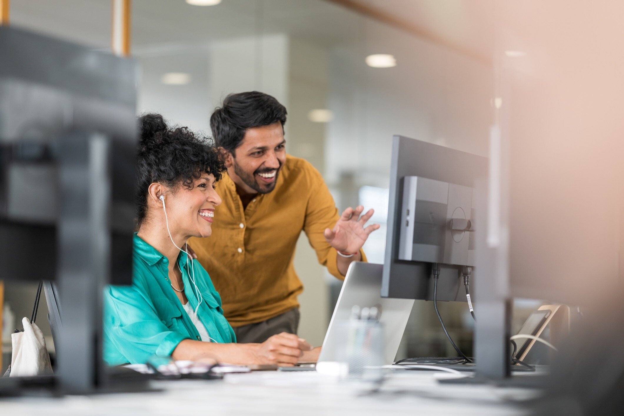 Coworkers in front of computer monitor in modern office chatting online_flipped