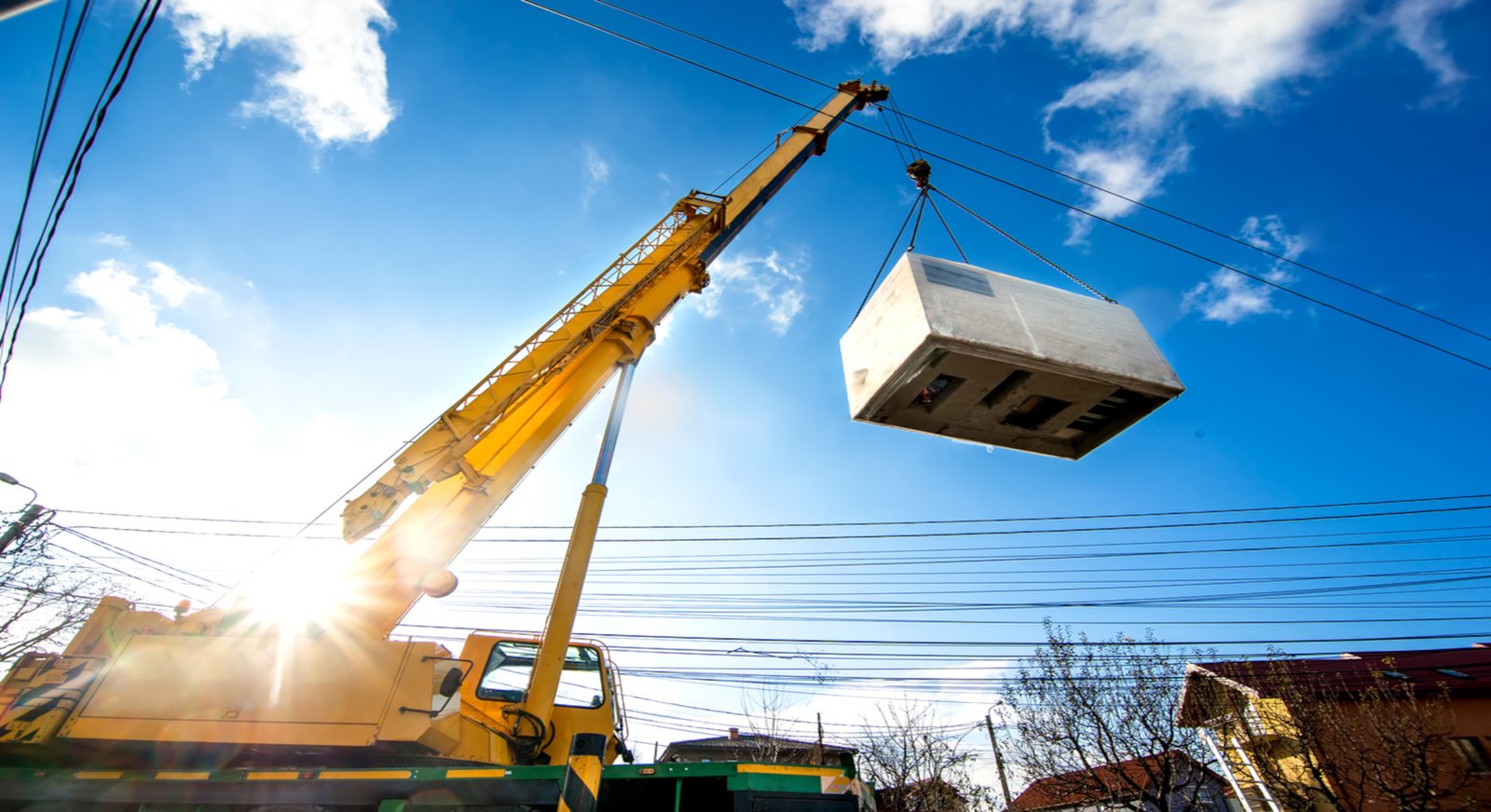 A big yellow crane lifts a crate into the air