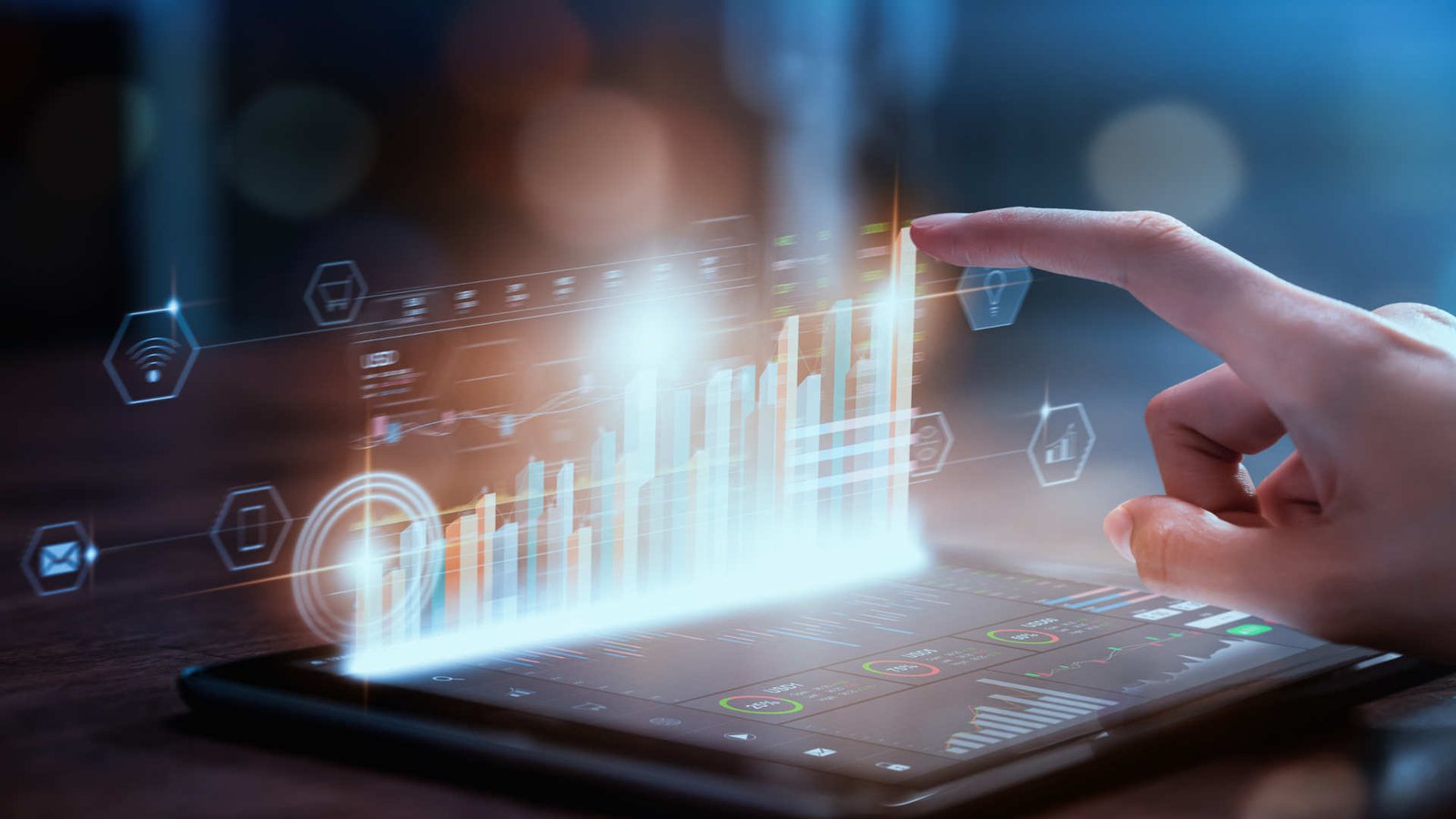 Hand reaches out to futuristic hologram that reaches out of a tablet lying flat on a desk