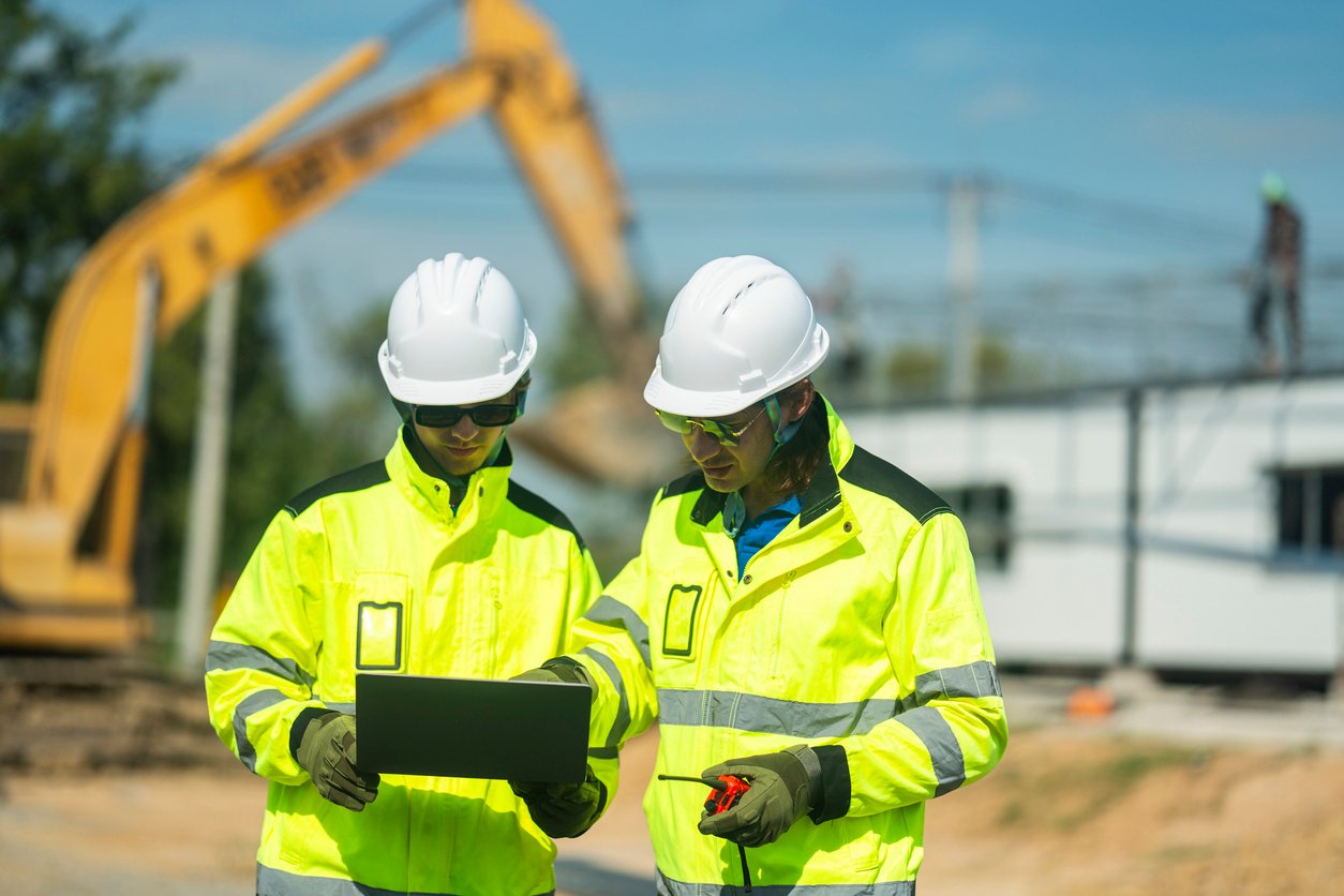 Two engineers in high vis vests with tablet on construction site