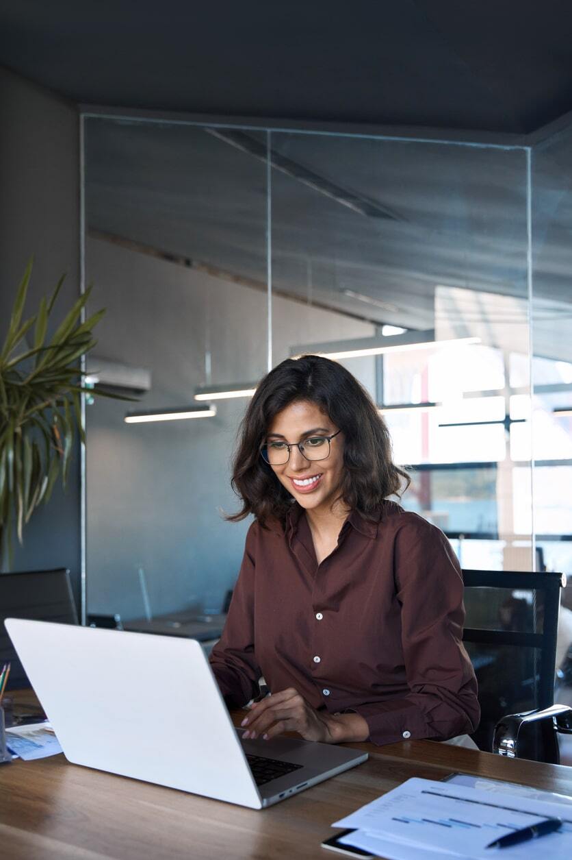 Young woman working on a laptop in a modern office setting-min